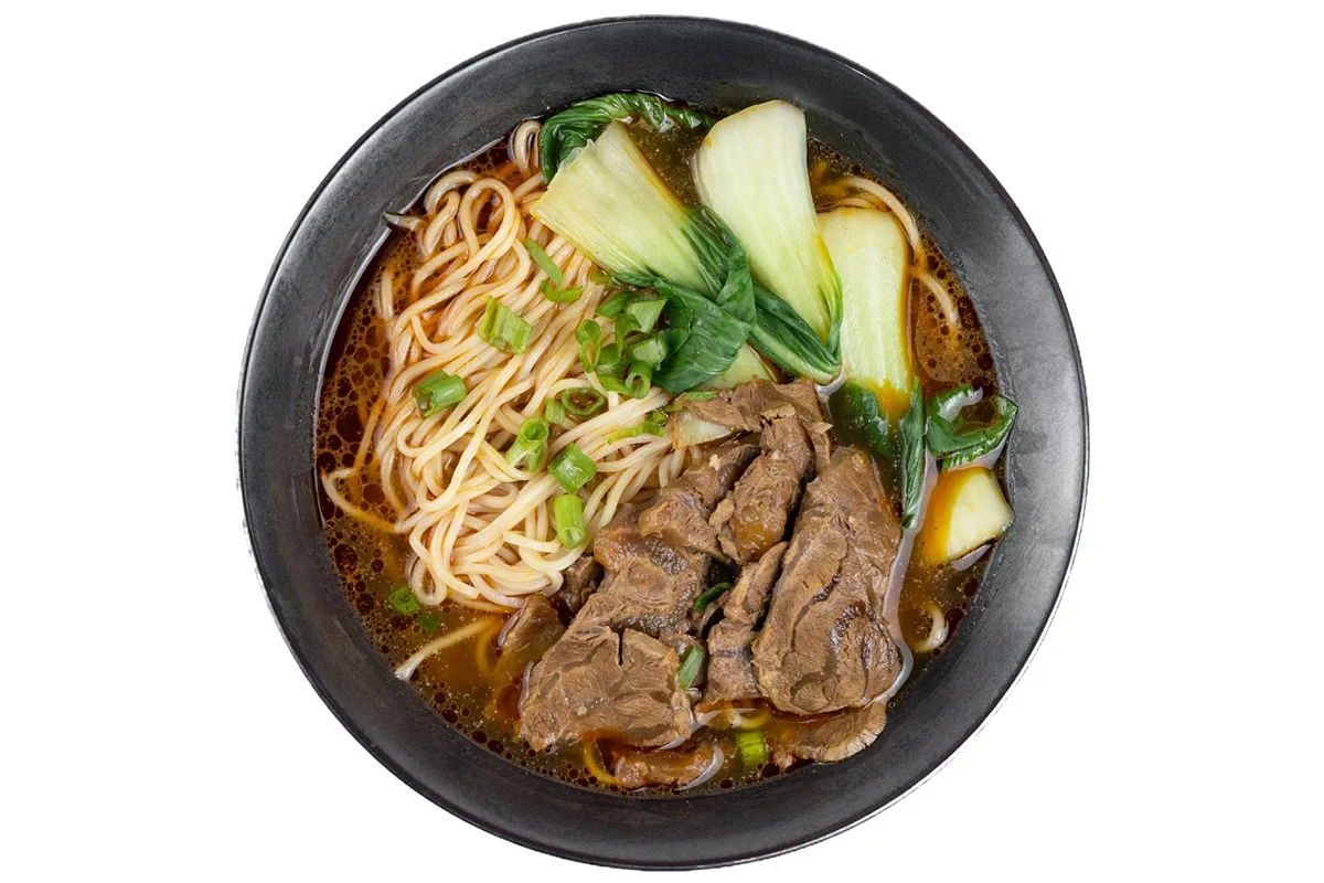 Thin beef noodles with bok choy in a black bowl at Super Taste.